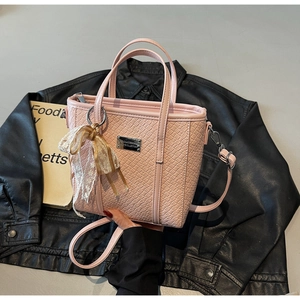 Dettaglio borsa shopper rosa intrecciata con placca d'argento e fiocco in pizzo