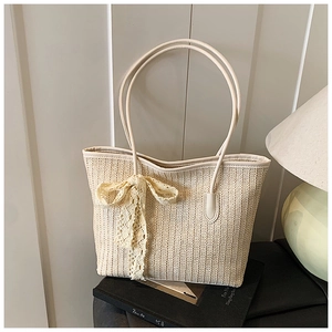 Gros plan d'un sac cabas tissé beige avec nœud en dentelle dans un décor de maison doux