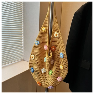 Detail of yellow hand-crocheted tote bag featuring colorful 3D floral accents and hollow mesh