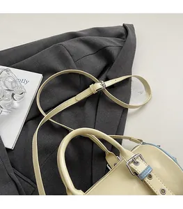 Detail of adjustable slim shoulder strap and silver metal buckle on beige Boston bag