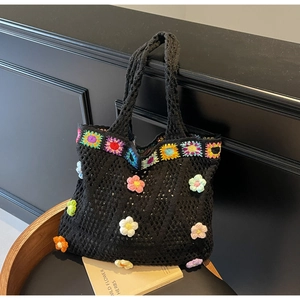 Dettaglio di borsa tote nera all'uncinetto con fiori colorati fatti a mano e margherite