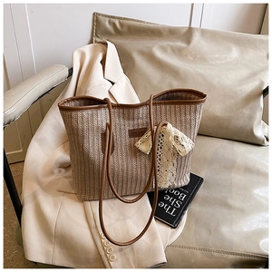 Détail d'un sac cabas tissé avec anses en cuir marron et nœud décoratif en dentelle