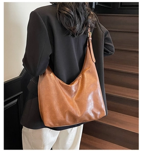 Rear view of model wearing a large brown PU leather hobo tote bag with a retro texture
