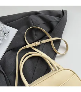 Close-up of beige leather handbag strap and fine stitching on a grey blazer