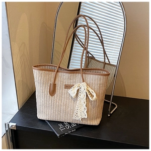 Détail du sac cabas en paille avec anses en cuir marron et ruban en dentelle décoratif