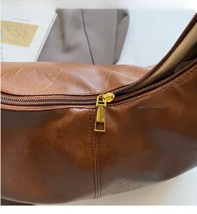 Close-up of smooth gold zipper slider and textured brown PU leather on tote bag