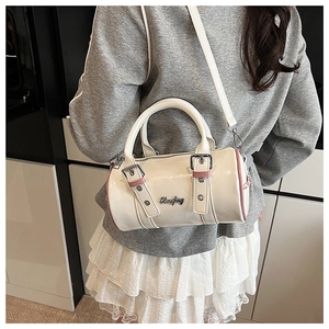 Detail of a chic cream cylinder Boston bag with pink piping and silver buckle straps