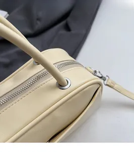 Detailed top view of beige litchi grain handbag showing metal zipper and handle texture