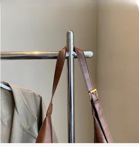 Detail of adjustable golden buckle and brown leather strap on a textured tote bag
