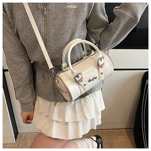 Detailed view of white glossy cylinder bag with pink piping on a model