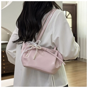 Détail du sac d'épaule rose brillant avec nœud en dentelle et perles sur le mannequin