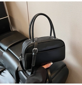Detail of black PU leather Boston pillow bag with dual handles and silver hardware