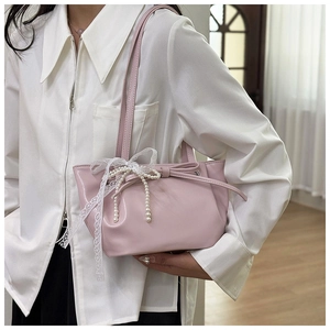 Sac seau plissé rose avec nœud en dentelle et perles porté sur l'épaule