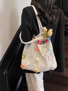 Borsa tote in maglia bianca con fiori all'uncinetto colorati indossata da una modella