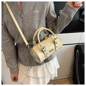 Detail of cream yellow mini barrel bag with blue piping and metallic brand logo
