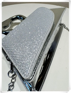 Macro view of silver rhinestone handbag with mirror finish and metallic top handle