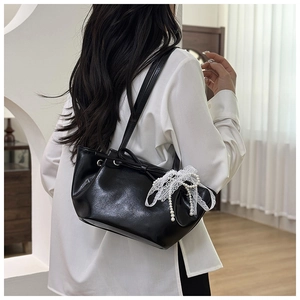 Détail du sac seau noir plissé avec nœud en dentelle blanche et breloque en perles