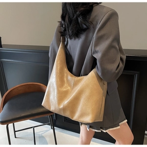 Detail of vintage khaki PU leather tote bag with natural texture shown on model