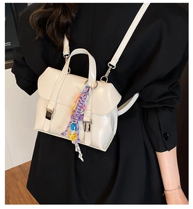 Detail of cream mini leather backpack with colorful woven charm and silver hardware