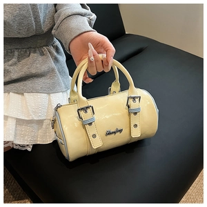 Detail showing the cream PU leather surface and blue buckle strap on the boston bag