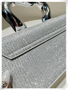 Close-up of silver sequin handbag featuring a polished metallic arched handle detail