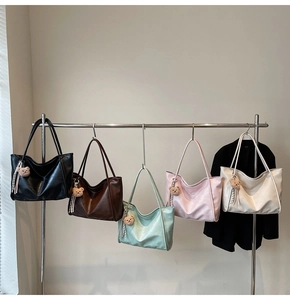 Row of colorful soft leather tote bags in macaron tones with cute bear charms on a rack