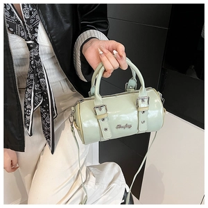Close-up of pistachio green mini Boston bag featuring silver metal logo and high-shine PU texture