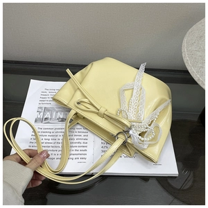 Détail du sac à bandoulière jaune pâle avec nœud en dentelle et pendentif en perles