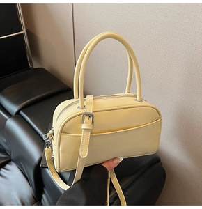 Close-up of yellow pebble grain pillow handbag with silver hardware and top handles