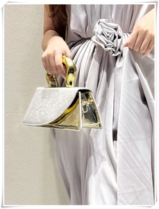 Close-up of sparkling rhinestone clutch bag with gold handle and metallic texture