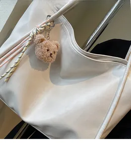 Detailed shot of soft white leather texture on large tote bag with cute bear charm