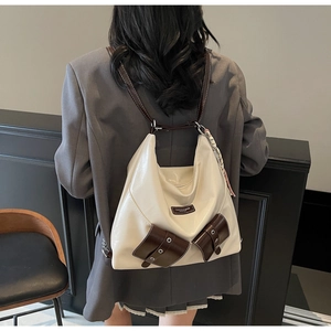 Détail d'un sac à dos en cuir blanc crème avec poches marron foncé et rabats à œillets