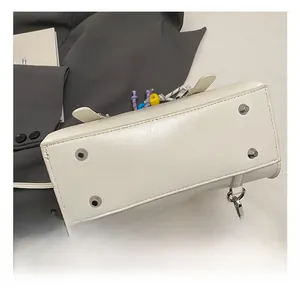 Detail shot of white leather bucket bag bottom with silver metal feet and strap hooks