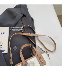Detailansicht der weißen Handtasche mit Schlangenmuster, verstellbarem Gurt und Perle