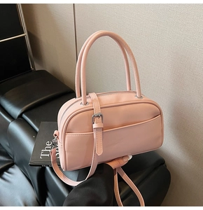 Pink leather pillow bag featuring a smooth finish, top handle, and adjustable shoulder strap