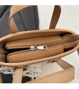 Detail der khakifarbene Tasche mit Silberreißverschluss, Spitze und Perlenanhänger
