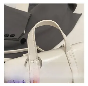 Detail of white leather handbag with silver rings and purple braided rope accent