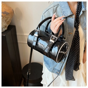 Detail of black glossy Boston bag with silver buckle and metallic logo on female model