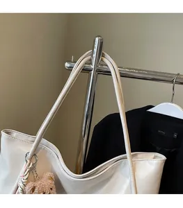 Detail of cream white tote bag with faux leather texture and a cute plush bear charm