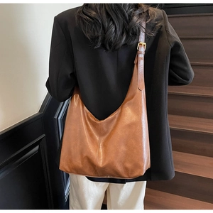 Detail of vintage brown PU leather tote bag with adjustable strap worn by model