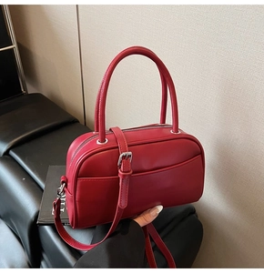 Detail of red leather Boston bag with rounded handles and silver hardware for women