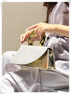 Detail of evening handbag with gold mirror finish and shimmering crystal flap