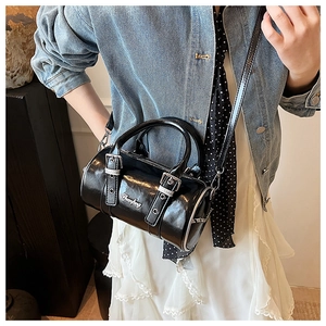 Detail showing high-gloss black Boston bag with metallic logo and adjustable strap