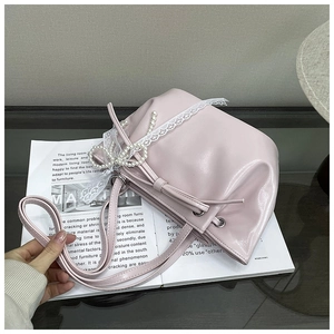 Détail du sac seau rose clair avec bordure en dentelle blanche et nœuds en perles