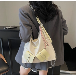 Détail d'un grand sac fourre-tout crème avec poches jaunes et chaîne sur le dos du mannequin
