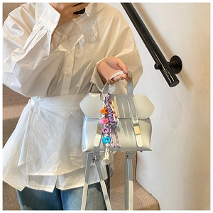 Close-up of light blue patent leather handbag with colorful letter charms on stairs