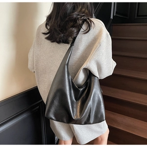 Detail view of large black PU leather moon tote bag with glossy texture on shoulder