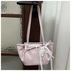 Détail du sac bandoulière plissé rose clair avec pendentif en perles et dentelle sur bois