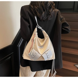 Détail d'un sac cabas blanc crème avec chaînes métalliques porté par un mannequin