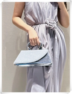 Detail of silver sequined trapezoid evening bag with oversized metal ring handle